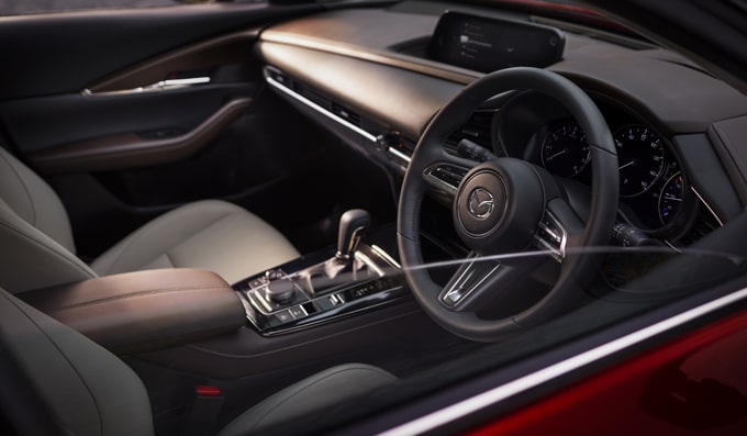 All-New Mazda CX-30 interior shot with front seats, steering wheel, dashboard and gearshift in view.